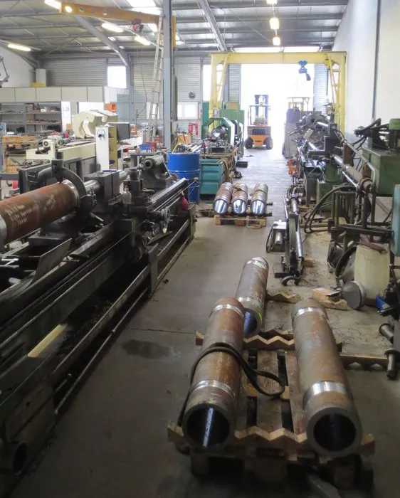 Atelier industriel – Vue d’un atelier avec plusieurs machines et pièces métalliques en cours de fabrication.